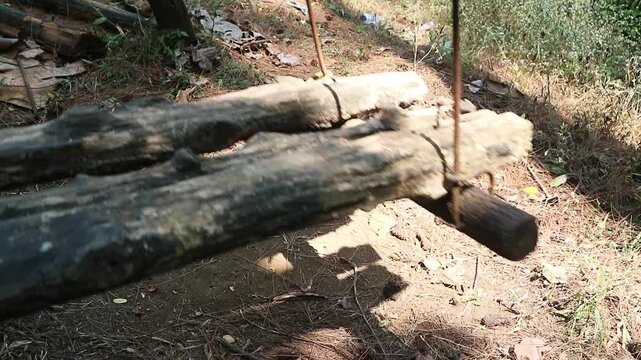 A rustic handmade wooden swing suspended by metal rods in a rural outdoor setting. perfect for concepts of childhood nostalgia, relaxation, freedom, and peaceful leisure.