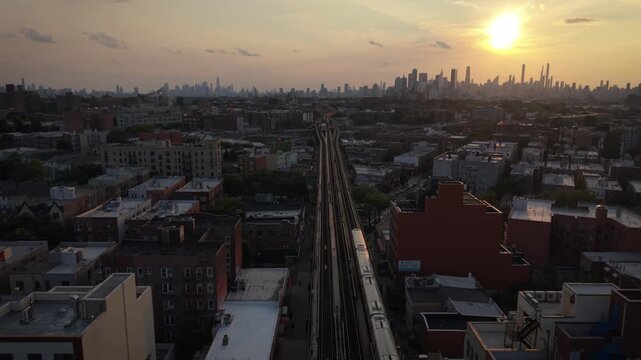 wider sunset aerial shot of elevated train in Jackson Heights headed for NYC