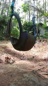 A handmade swing made from a recycled rubber tire hanging in a forest. perfect for concepts of childhood nostalgia, relaxation, freedom, and peaceful leisure.