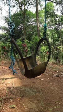 A rustic handmade tire swing hanging from a tree in a forest. perfect for concepts of childhood nostalgia, relaxation, freedom, and peaceful leisure.