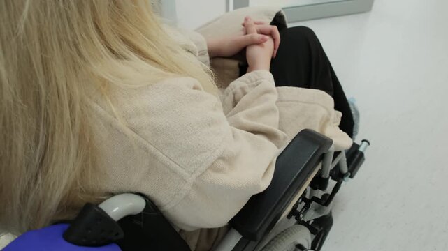 Nurse escorts disabled patient toward sterile ultrasound procedure room. Patient quietly waits for scheduled ultrasound procedure. Slow motion