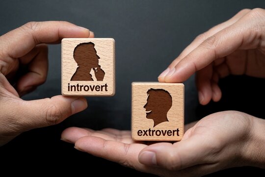 Human hands hold wooden blocks with introvert, extrovert labels. Person profiles show different personality types on timber cubes. Concept of psychology, mental health, social behavior, character