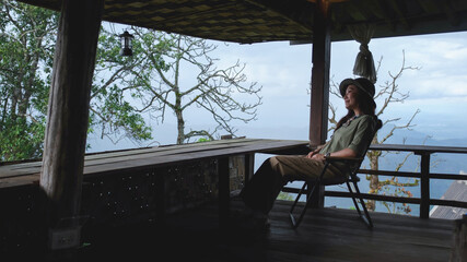 Fototapeta premium Portrait of a woman sitting on wooden balcony and looking at mountain views