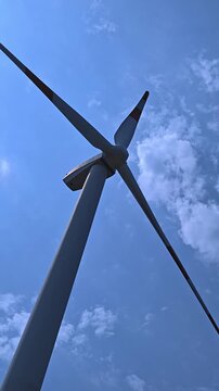 Wind turbine blades spinning against a blue sky