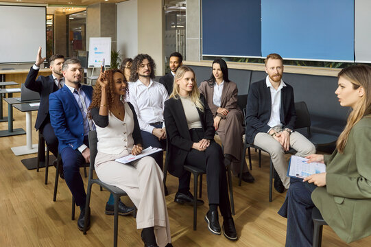 Team business training workshop meeting speaker audience. In a modern office employees engage with a coach, asking questions and taking notes. Clear concept of corporate learning and teamwork.