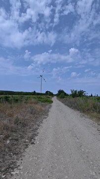 A walk along a country road on a sunny day in the direction of a wind turbine