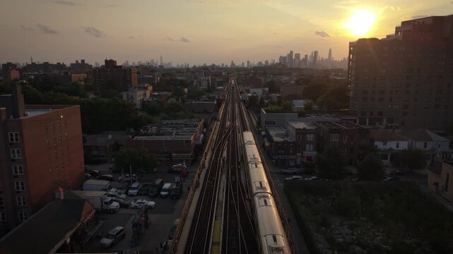 wider sunset aerial shot of elevated train in Jackson Heights bound for NYC