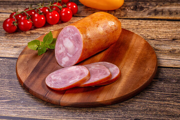 Sliced sausage on wooden cutting board with cherry tomatoes and basil © Andrei Starostin