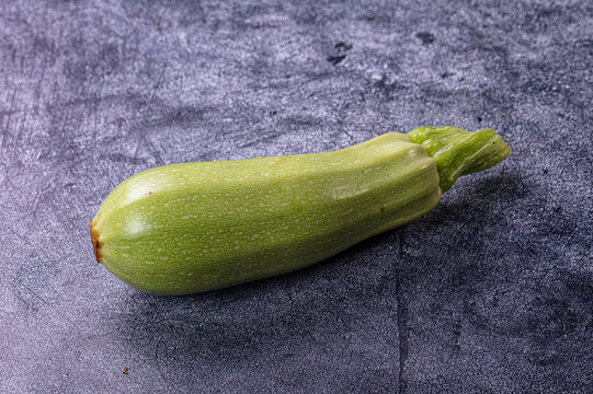 Fresh green zucchini on textured dark surface