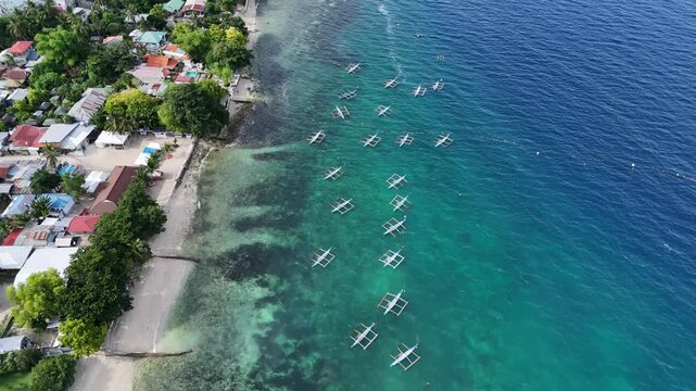 Outrigger boats moored off a village beach in turquoise shallows