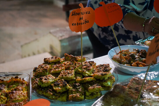 Close-up of traditional Greek pumpkin pie squares on a platter. Labeled 'Batsina with Pumpkin' in greek. Cretan gastronomy and greek cuisine.