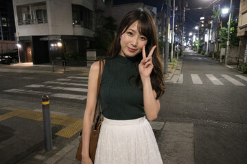 Fototapeta premium 緑トップスと白スカートで夜道に立つ女性