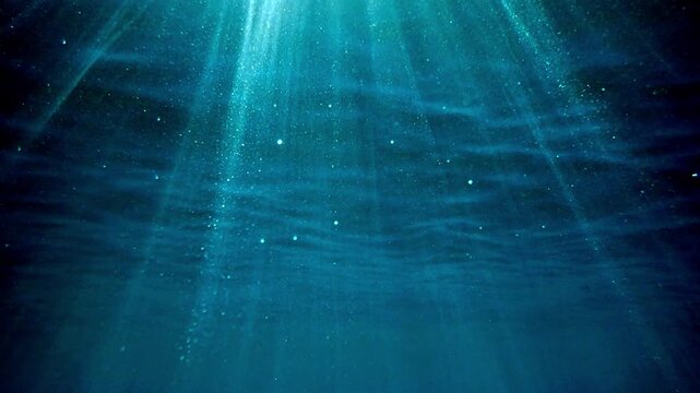 Dark blue ocean surface seen from underwater. Sunlight rays under water. Underwater blue background in sea bottom. Sunbeam and ripples. wave lights. Slow motion. Mediterranean sea. Real video water.