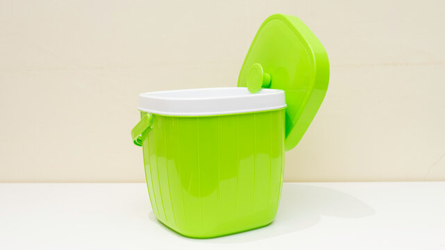 Green plastic container stands on a white surface.