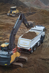 Excavator loading dirt into tipper truck at construction site © Tatiana