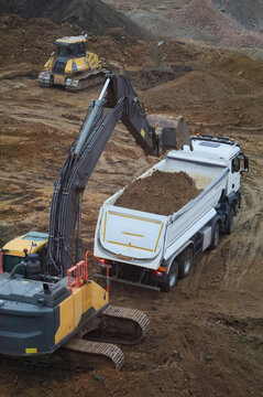 Excavator loading dirt into tipper truck at construction site