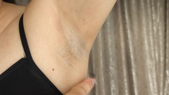 Woman touching underarm hair, body hair removal, waxing, personal hygiene and underarm care concept.