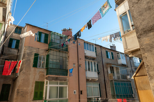 Facciate storiche con persiane verdi e panni stesi al sole tra i palazzi. Scena urbana autentica ideale per temi vita quotidiana, Mediterraneo, architettura e atmosfera residenziale.