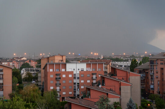 Edifici residenziali illuminati sotto un cielo scuro e tempestoso. Ideale per temi meteo, citt&agrave;, atmosfera drammatica, paesaggio urbano, clima e fotografia ambientale.