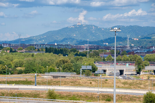 Veduta urbana con svincolo autostradale, edifici e aree verdi ai piedi della collina di Superga. Sullo sfondo la Basilica, ideale per temi citt&agrave;, infrastrutture, paesaggio, mobilit&agrave; e fotografia