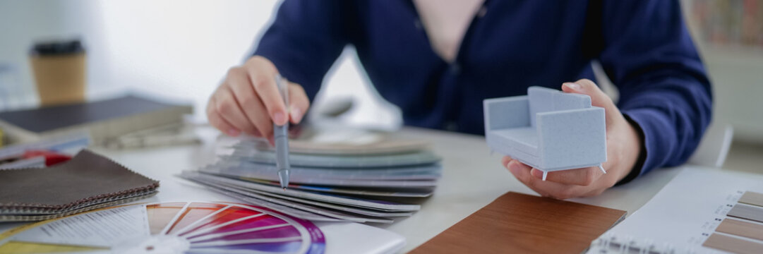 Furniture designer selecting fabric samples and paint chips for interior project at modern studio desk