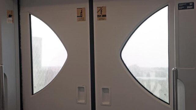 Interior view of automatic sliding doors on an elevated subway train moving through a city