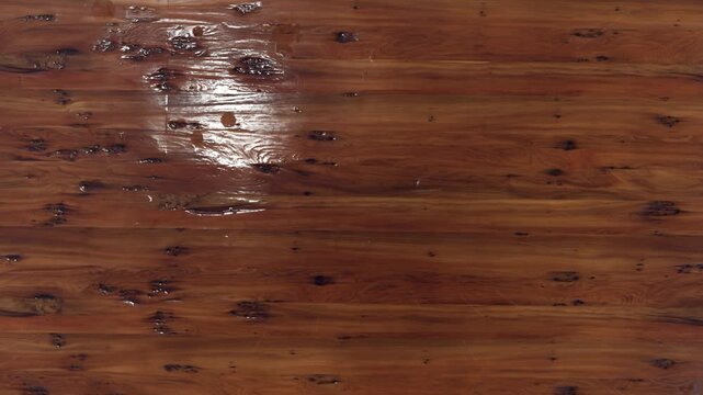 Close-up slow motion water droplet splashing on dark stained wooden surface texture