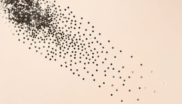 Flat lay of scattered silver and gold star sequins on a soft beige background