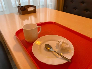 Fotobehang Horeca Empty coffee cup and dirty plate on red tray after meal. Finished dinner on wooden table in cozy cafe with warm lighting. Restaurant service and catering concept.  © marinasokolchik