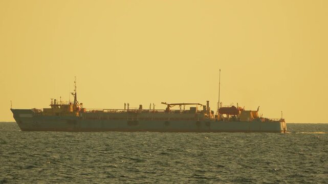 Dredger ship ocean, large industrial vessel sails on the sea at golden sunset hour, marine work.