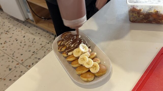 Mini Pancakes with Fresh Banana Slices Decorated with Chocolate Topping