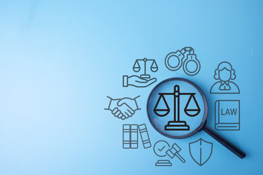 Magnifying glass focusing on a justice scale icon surrounded by judge, law book, and handshake graphics on a blue background. Concept of legal services, justice system, and law enforcement.