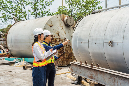 Industrial Engineers Inspecting Large Storage Tank at Factory Site