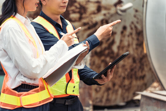 Industrial Engineers Inspecting Large Storage Tank at Factory Site