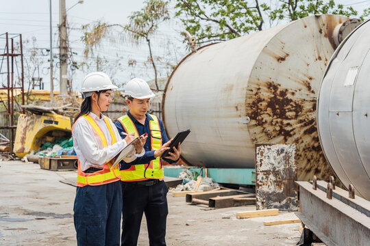 Industrial Engineers Inspecting Large Storage Tank at Factory Site