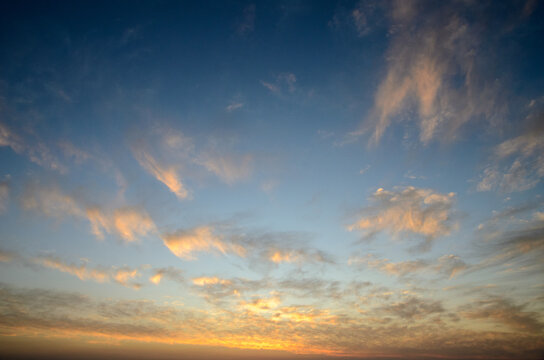 Colorful clouds dance across the evening sky as the sun sets on a tranquil horizon