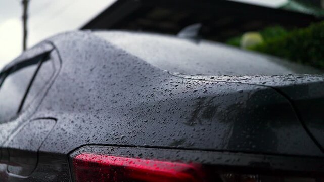Rear view of a modern car covered in raindrops after rain. Water repellent coating, ceramic protection, auto detailing, and rainy season weather concept. 