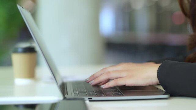 Close-up of Asian businesswoman using mobile phone, texting and cheating on her smartphone while outside office.