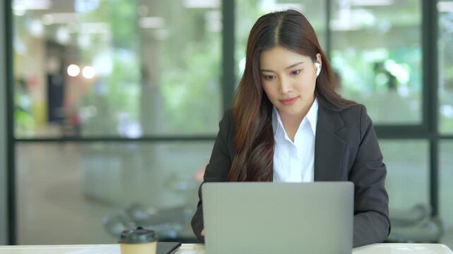  Asian businesswoman working at desk using laptop and notebook talking to client or office building, slow motion footage