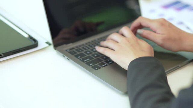 Close-up of Asian businesswoman using mobile phone, texting and cheating on her smartphone while outside office.