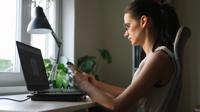 Woman checking mobile phone while working