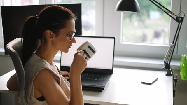Young businesswoman drinking coffee while working