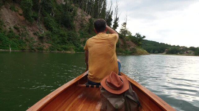 Rear view of solo canoe adventurer paddling on forest lake