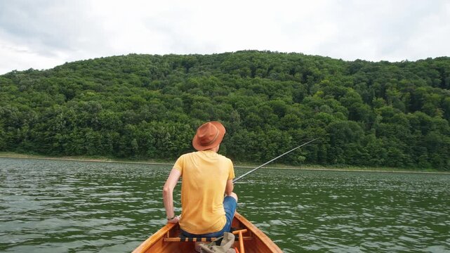 Rear view of man fishing from wooden canoe