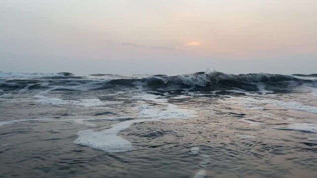 Tranquil sunset surf on Goa coastline with soft sky tones and rolling foam, beach evening mood vertical 4K B-roll
