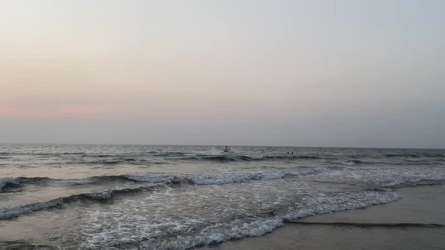 Tranquil sunset surf on Goa coastline with soft sky tones and rolling foam, beach evening mood vertical 4K B-roll