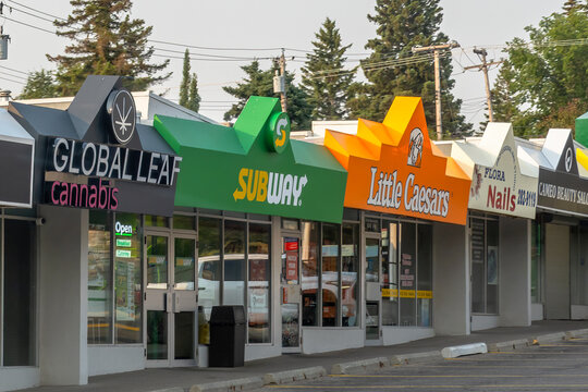 Calgary, Alberta, Canada. August 15, 2026. Exterior storefronts of retail strip mall businesses including Subway and Little Caesars.