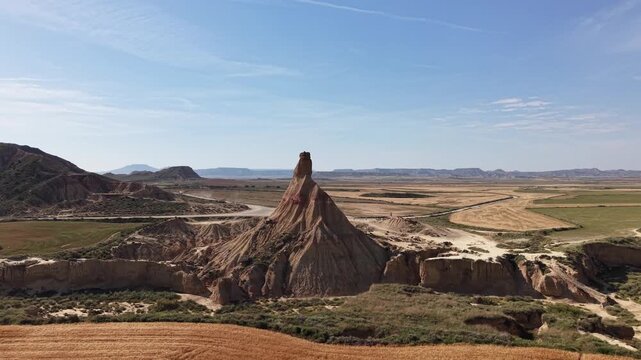 Aerial view of an isolated rock spire in a desert badlands landscape