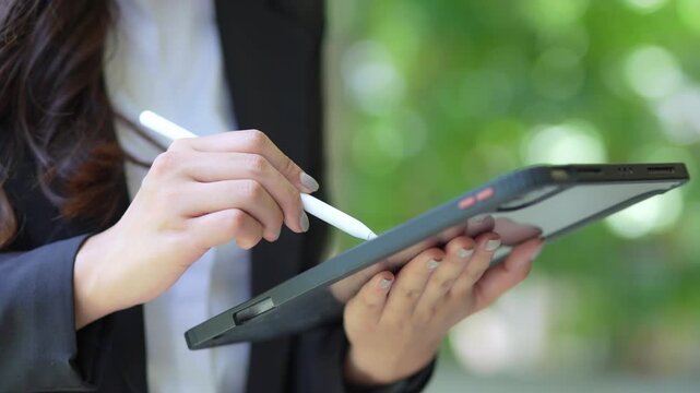 Elegant businesswoman in suit using digital tablet outside office