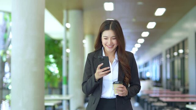 Close-up of Asian businesswoman using mobile phone, texting and cheating on her smartphone while outside office.